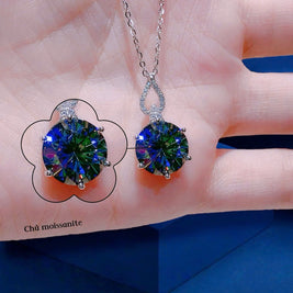 Multicolored gemstone earrings held against a hand with a blue background
