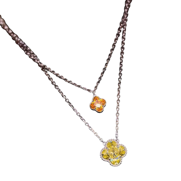 Necklace with two floral pendants, one yellow and one orange, on a white background.