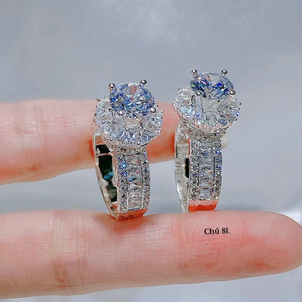 Pair of diamond earrings held between fingers against a neutral background