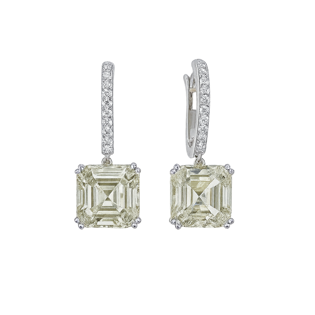 Pair of diamond earrings with green gemstones on a white background