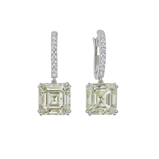Pair of diamond earrings with green gemstones on a white background