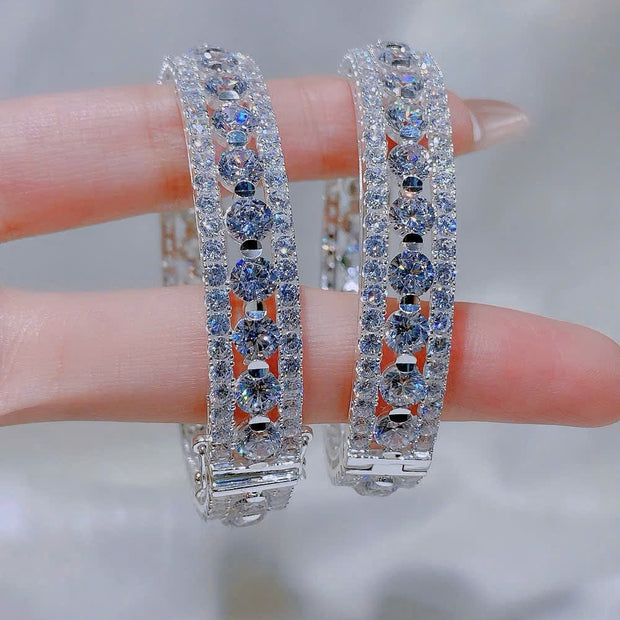 Pair of diamond hoop earrings held between fingers against a neutral background