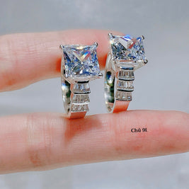 Pair of diamond ring held between fingers against a neutral background