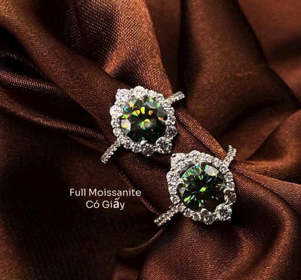 Pair of earrings with green gemstones on a brown fabric background