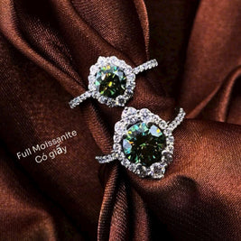 Pair of earrings with green gemstones on a brown fabric background