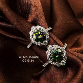 Pair of earrings with green gemstones on a brown fabric background