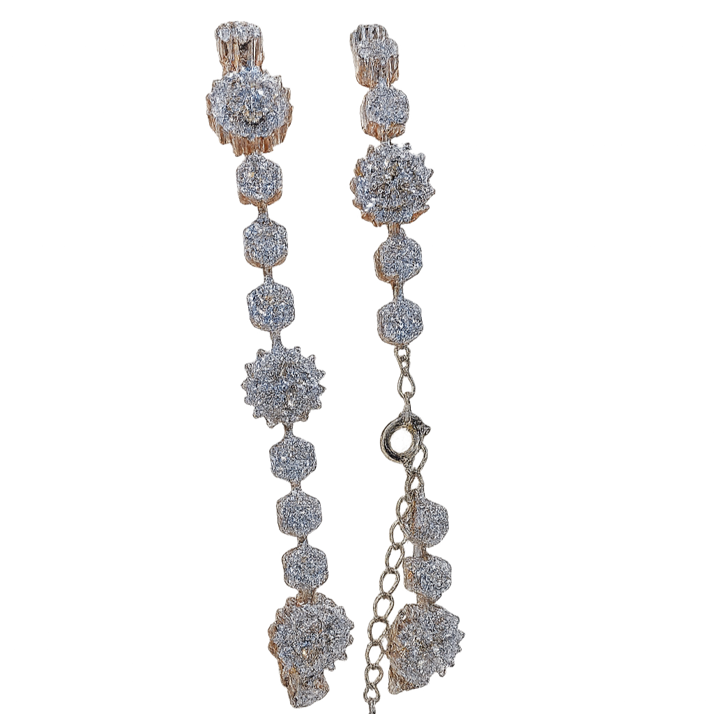 Pair of long, dangling earrings with diamond-like stones on a white background