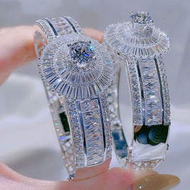 Pair of silver bracelet with clear gemstones on a blurred background