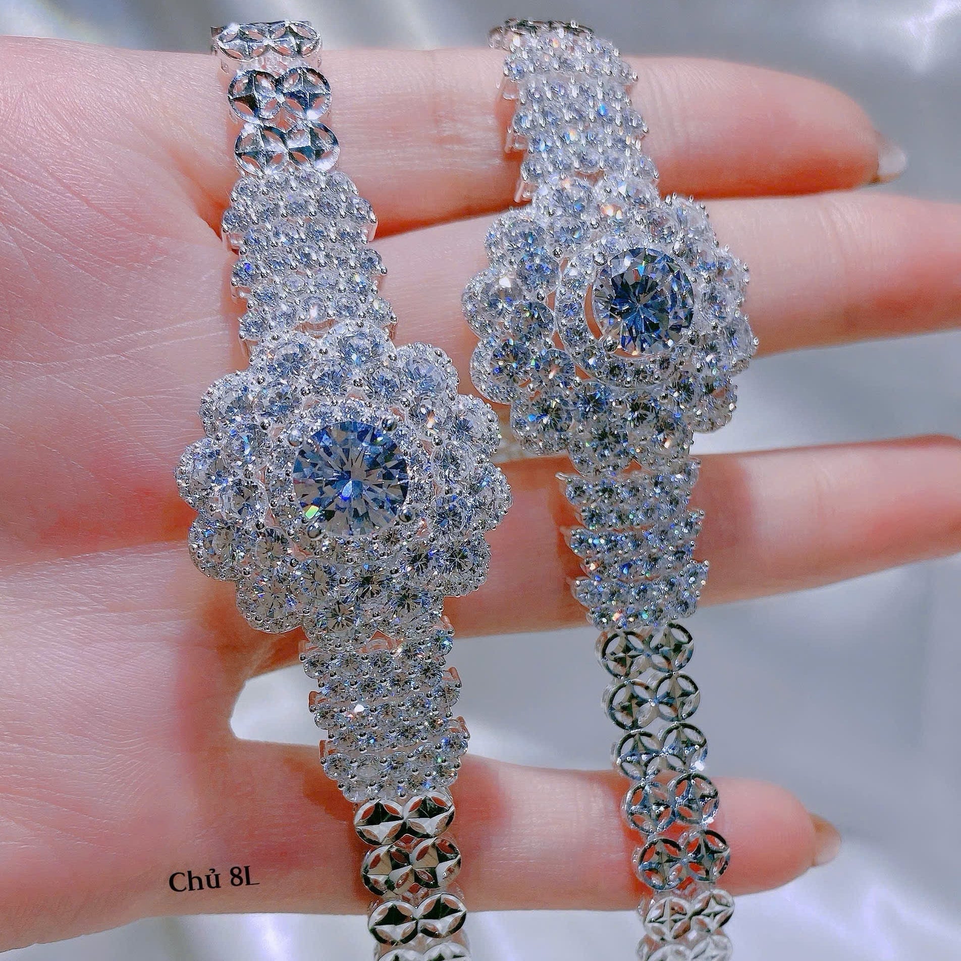 Pair of silver earrings with gemstones held between fingers against a neutral background