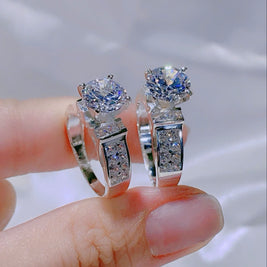 Pair of silver earrings with gemstones held between fingers against a neutral background
