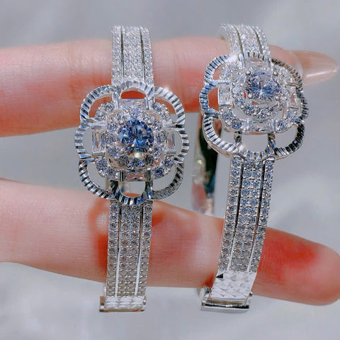 Pair of silver earrings with gemstones held between fingers against a neutral background