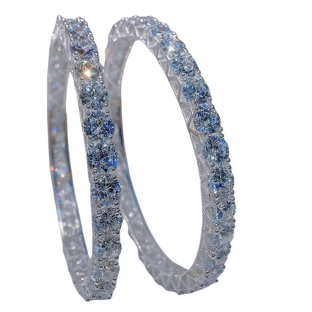 Pair of silver hoop earrings with blue gemstones on a white background