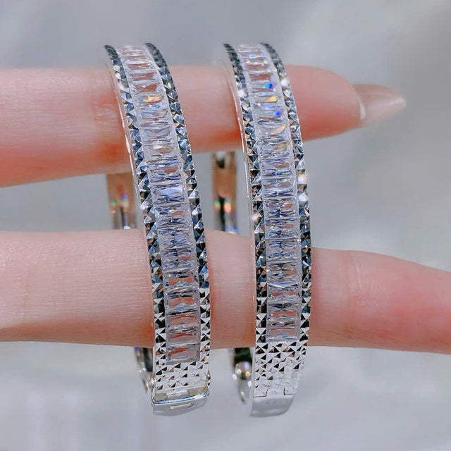 Pair of silver hoop earrings with clear gemstones on a blurred background