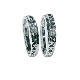 Pair of silver rings with geometric designs on a green background