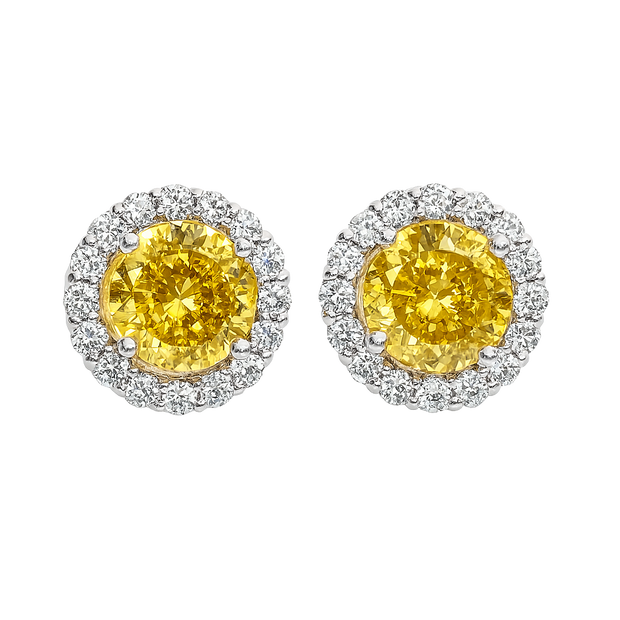 Pair of yellow gemstone earrings with silver halo on a white background