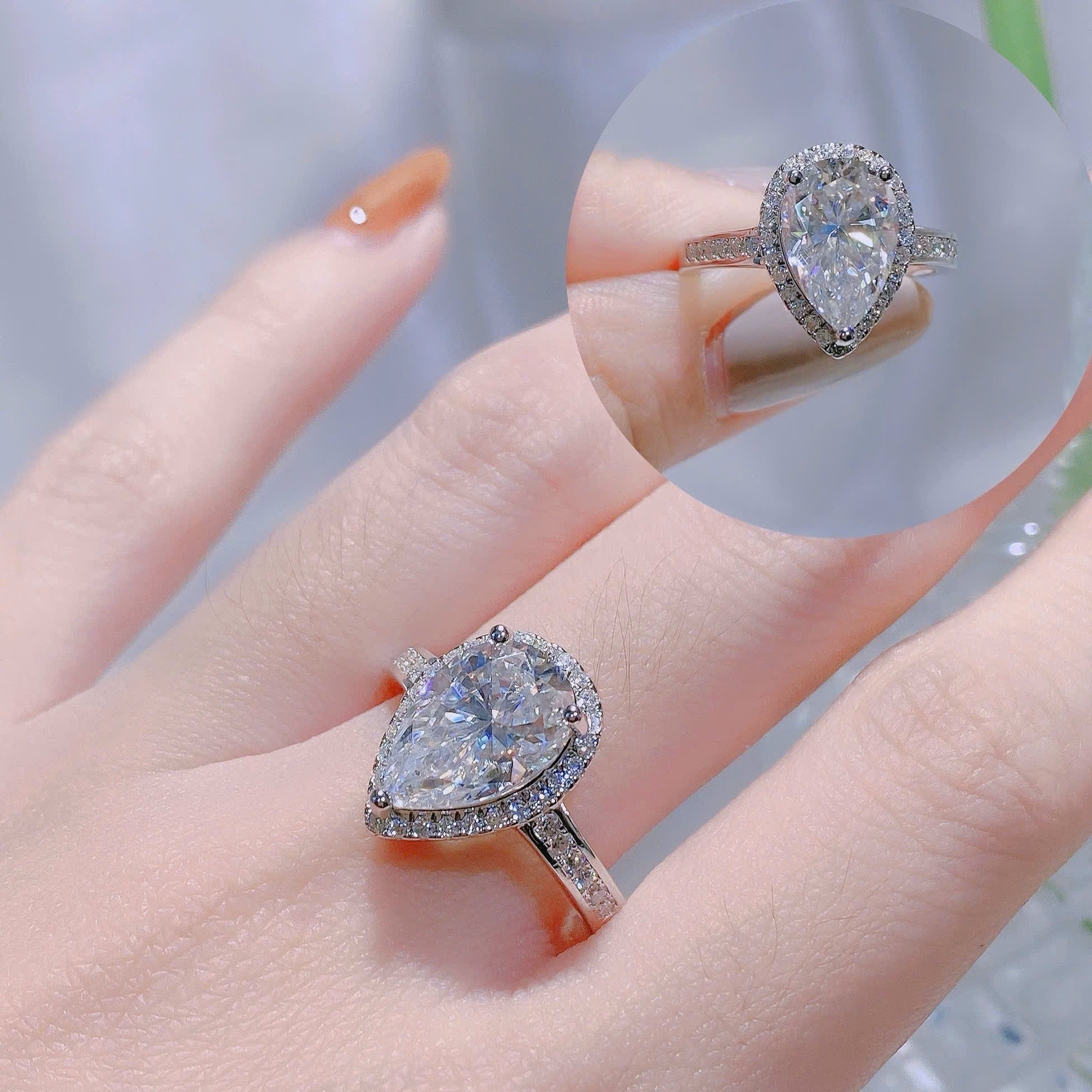 Pear-shaped diamond ring on a finger with a close-up inset.