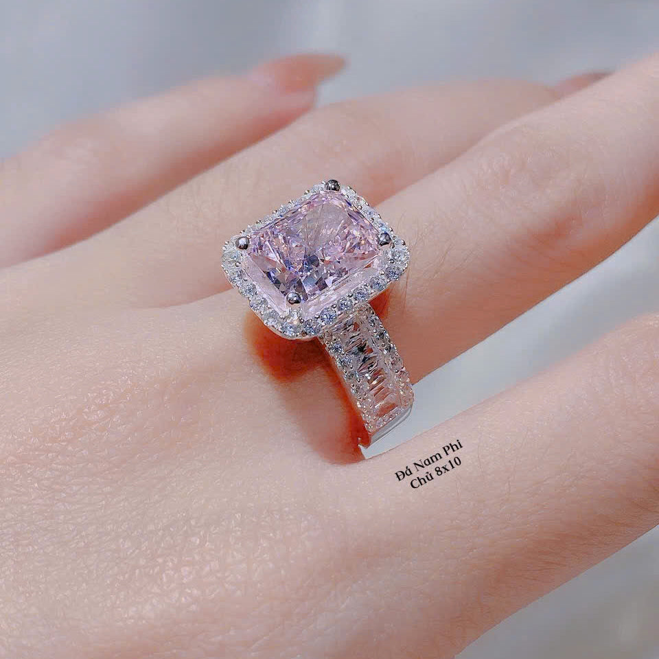 Pink diamond ring on a finger with a blurred background