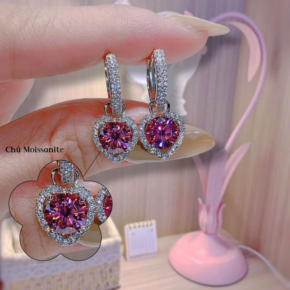 Pink gemstone earrings held by a hand with a blurred background