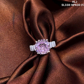 Pink gemstone ring with silver band on brown fabric, brand 'HLJ' visible