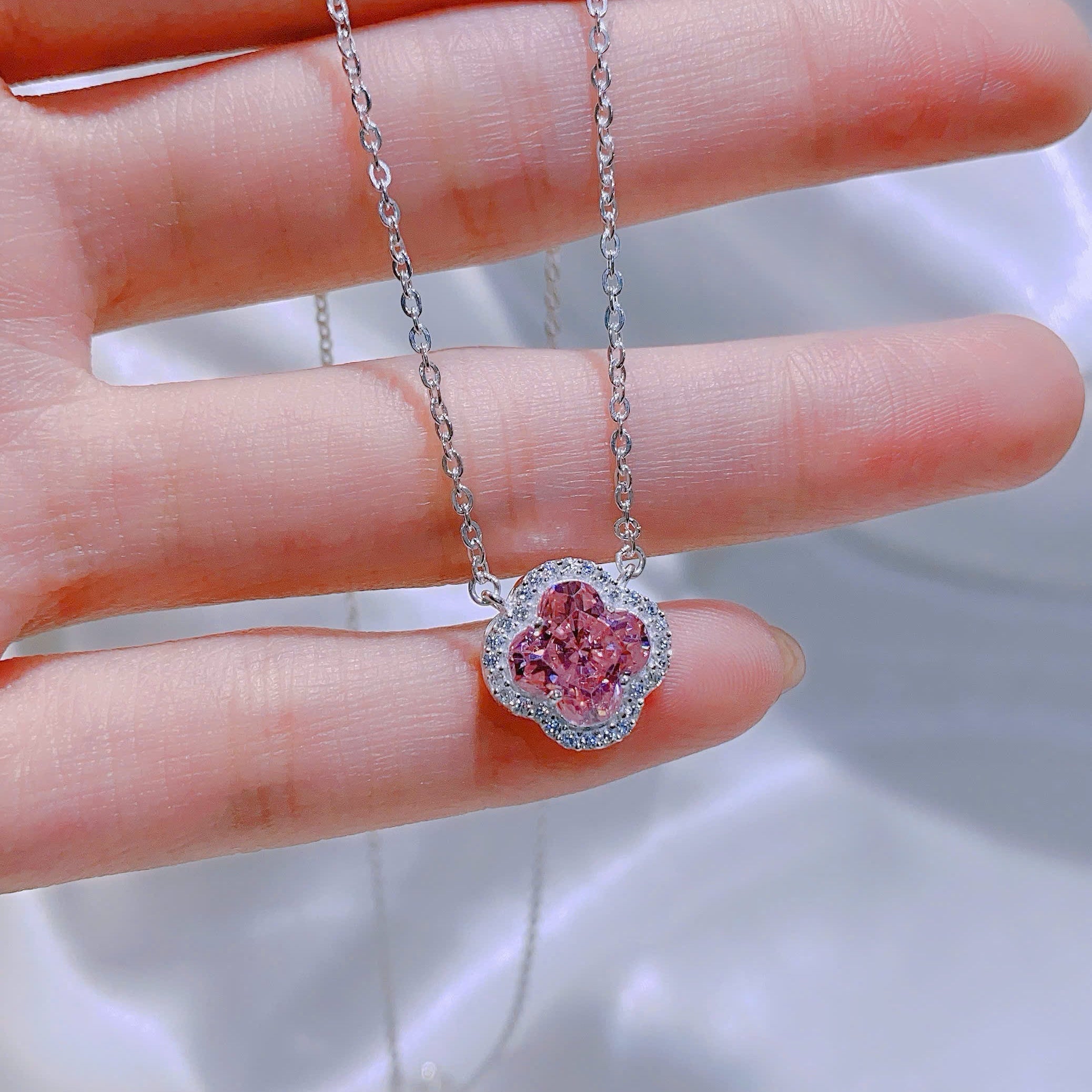 Pink heart-shaped gemstone necklace on a hand with a blurred background