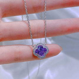 Purple heart-shaped pendant on a silver chain held between fingers