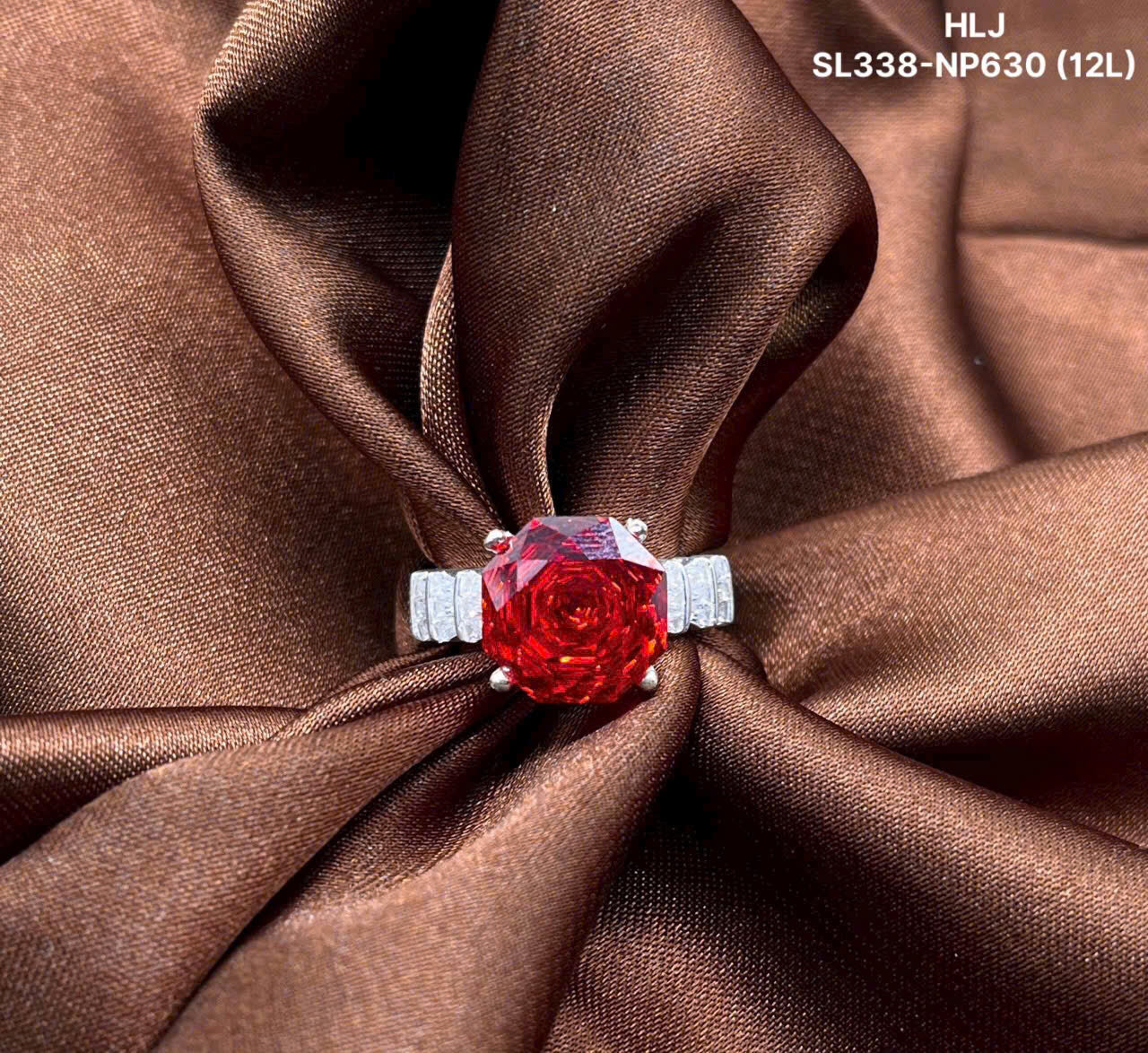 Red gemstone ring with silver setting on brown fabric