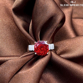 Red gemstone ring with silver setting on brown fabric