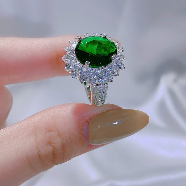 Ring with a green gemstone held by a hand against a blurred background