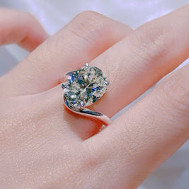 Ring with a large diamond on a person's finger against a neutral background