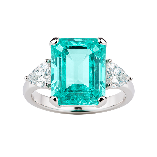 Ring with a large emerald-cut green gemstone and smaller clear stones on a white background