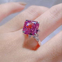 Ring with a large pink gemstone on a hand against a neutral background