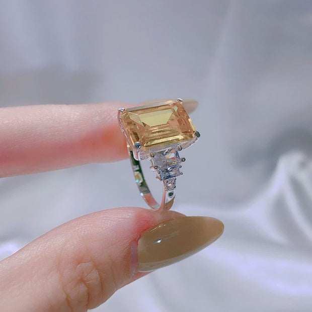 Ring with a large square-cut gemstone held between fingers against a neutral background