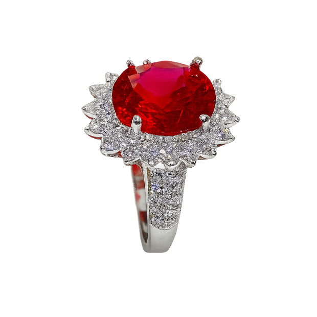 Ring with a red gemstone and diamond-studded band on a white background