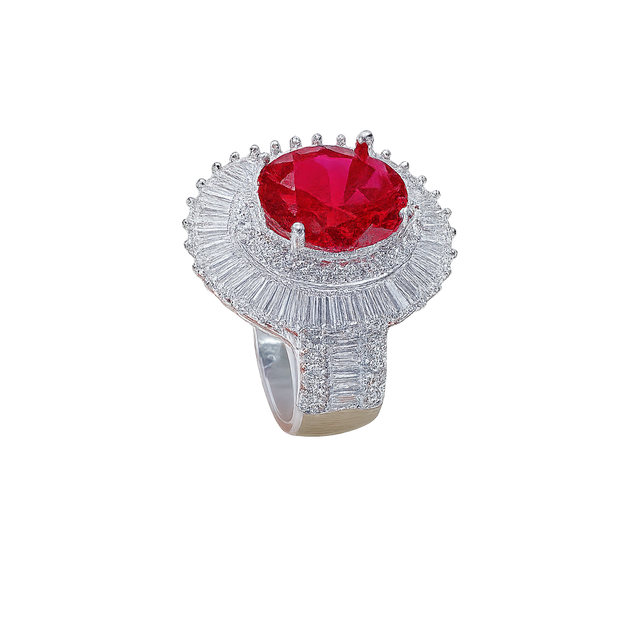 Ring with a red gemstone and diamond-studded band on a white background