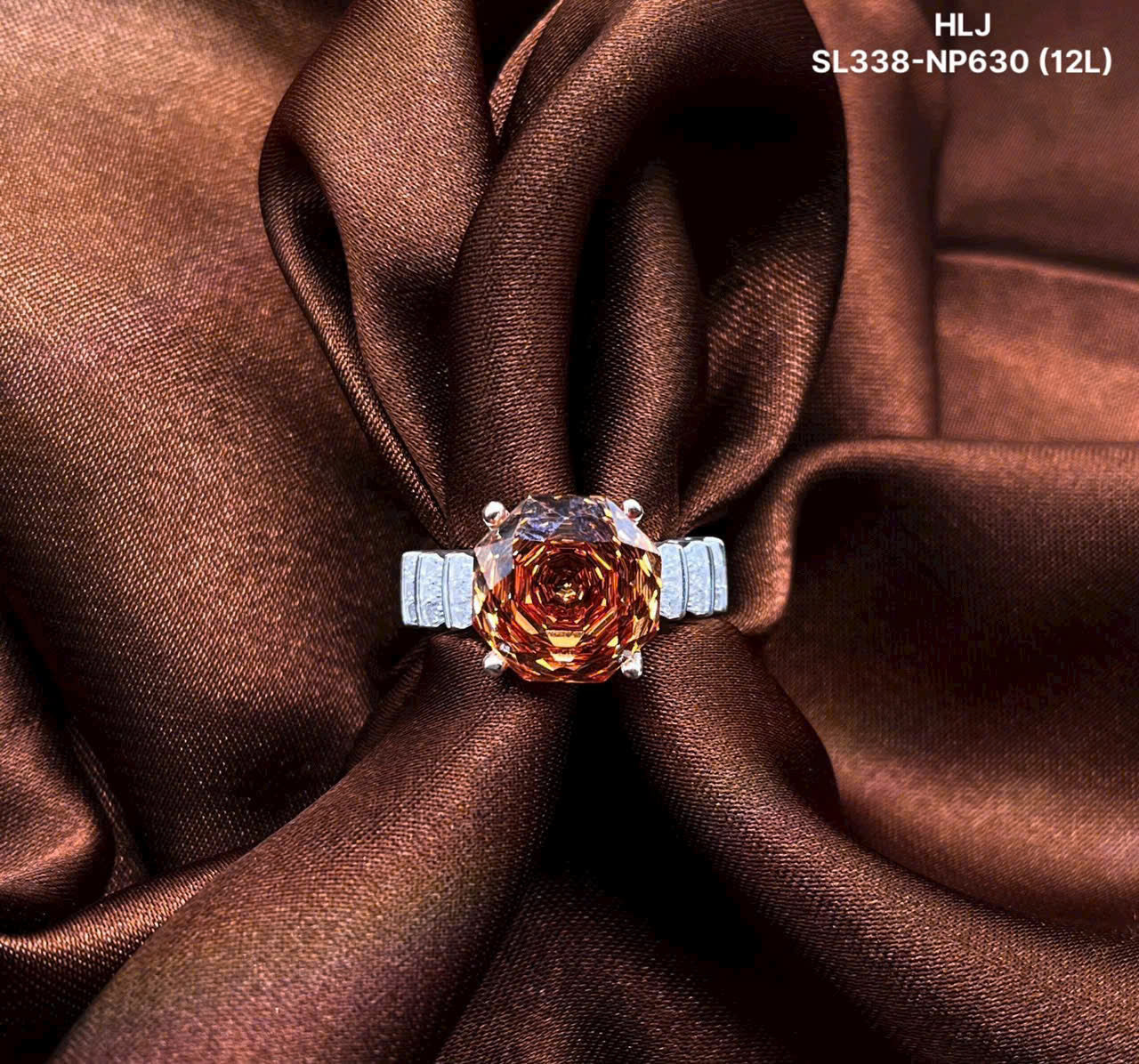 Ring with a rose-shaped gemstone on brown fabric, featuring brand 'HLJ'.