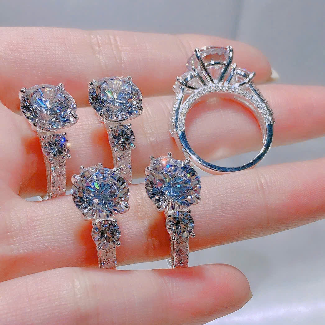 Set of diamond earrings and ring held on a hand with a blurred background