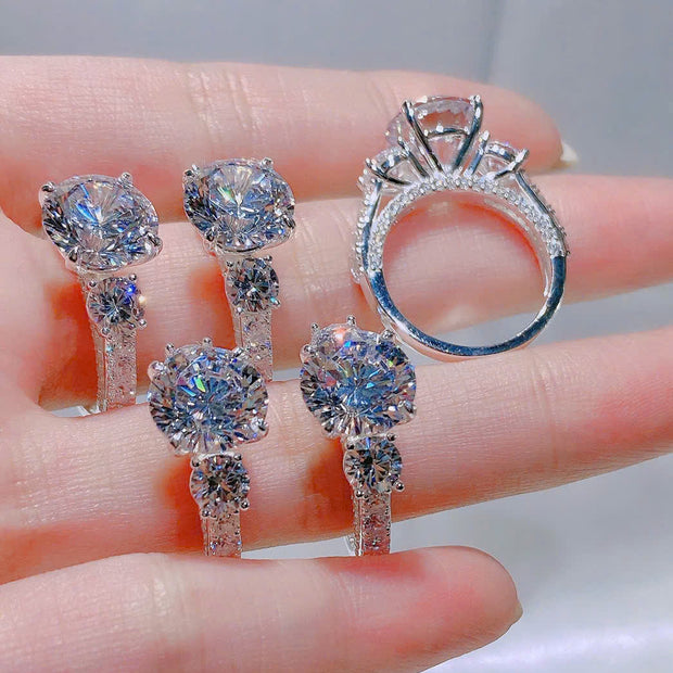 Set of diamond earrings and ring held on a hand with a blurred background