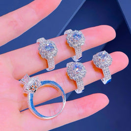 Set of diamond earrings and ring on a hand against a blue background