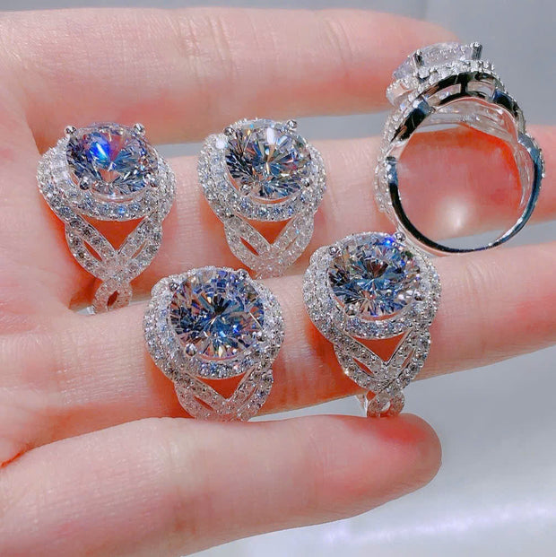 Set of diamond jewelry including earrings and a ring on a hand.