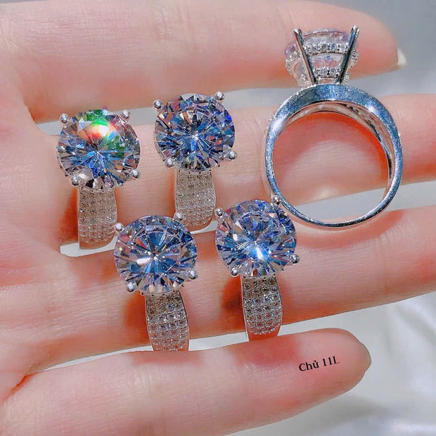 Set of diamond jewelry including rings and earrings on a hand.