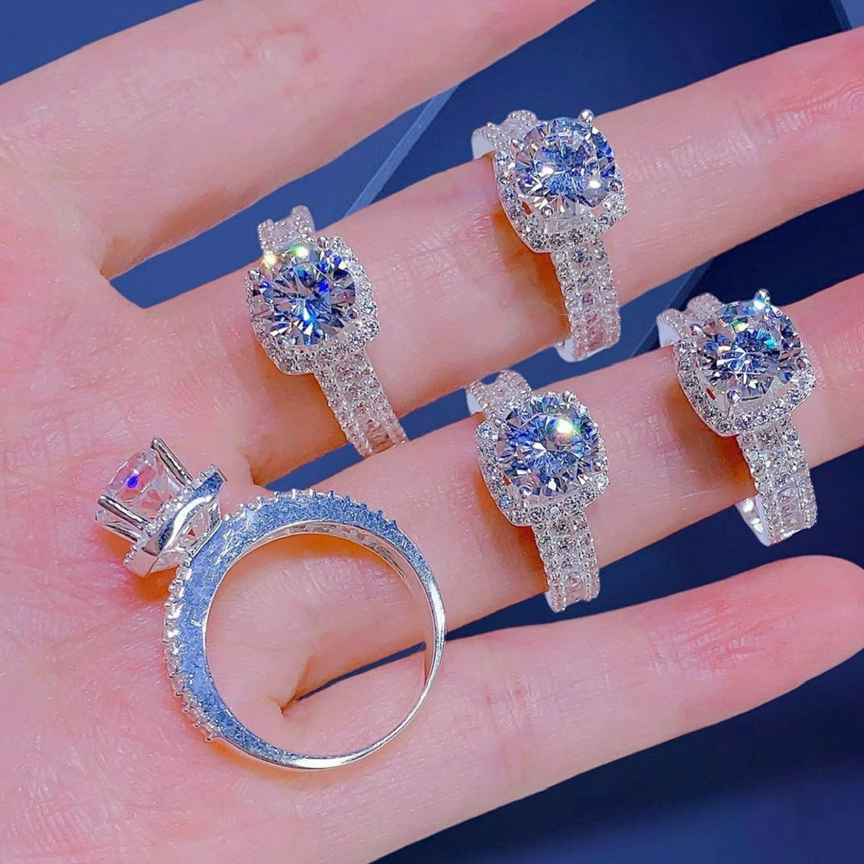 Set of diamond rings displayed on a hand against a blue background