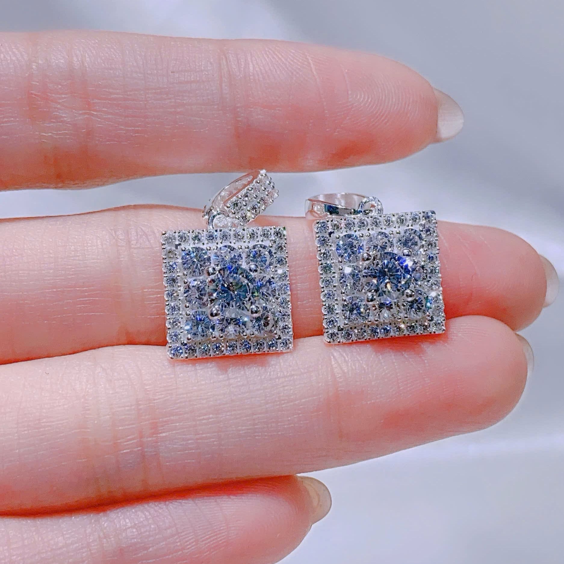 Set of silver earrings with clear gemstones on a white background