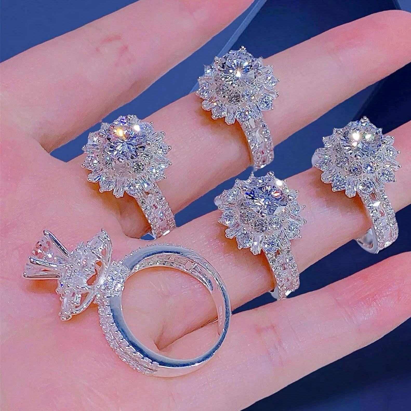 Set of silver rings on a hand with a blue background