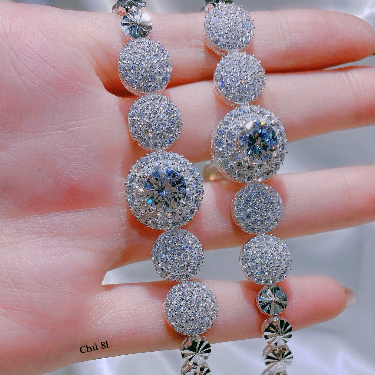 Silver beaded necklace held on a hand with a blurred background