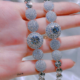 Silver beaded necklace held on a hand with a blurred background