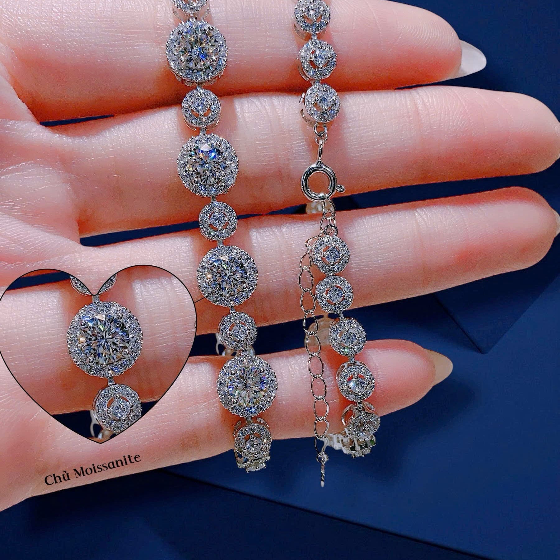 Silver bracelet and earrings on a hand with a blue background