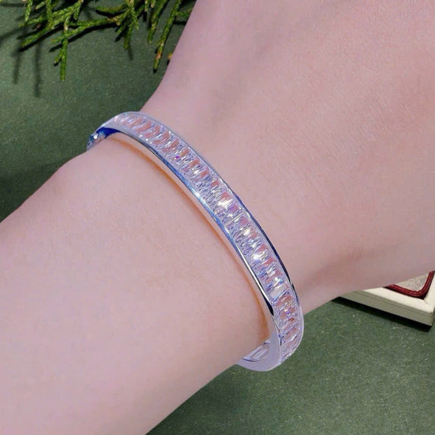 Silver bracelet on a wrist with a green background