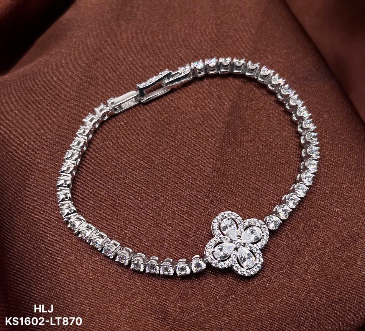 Silver bracelet with a floral clasp on a brown fabric background