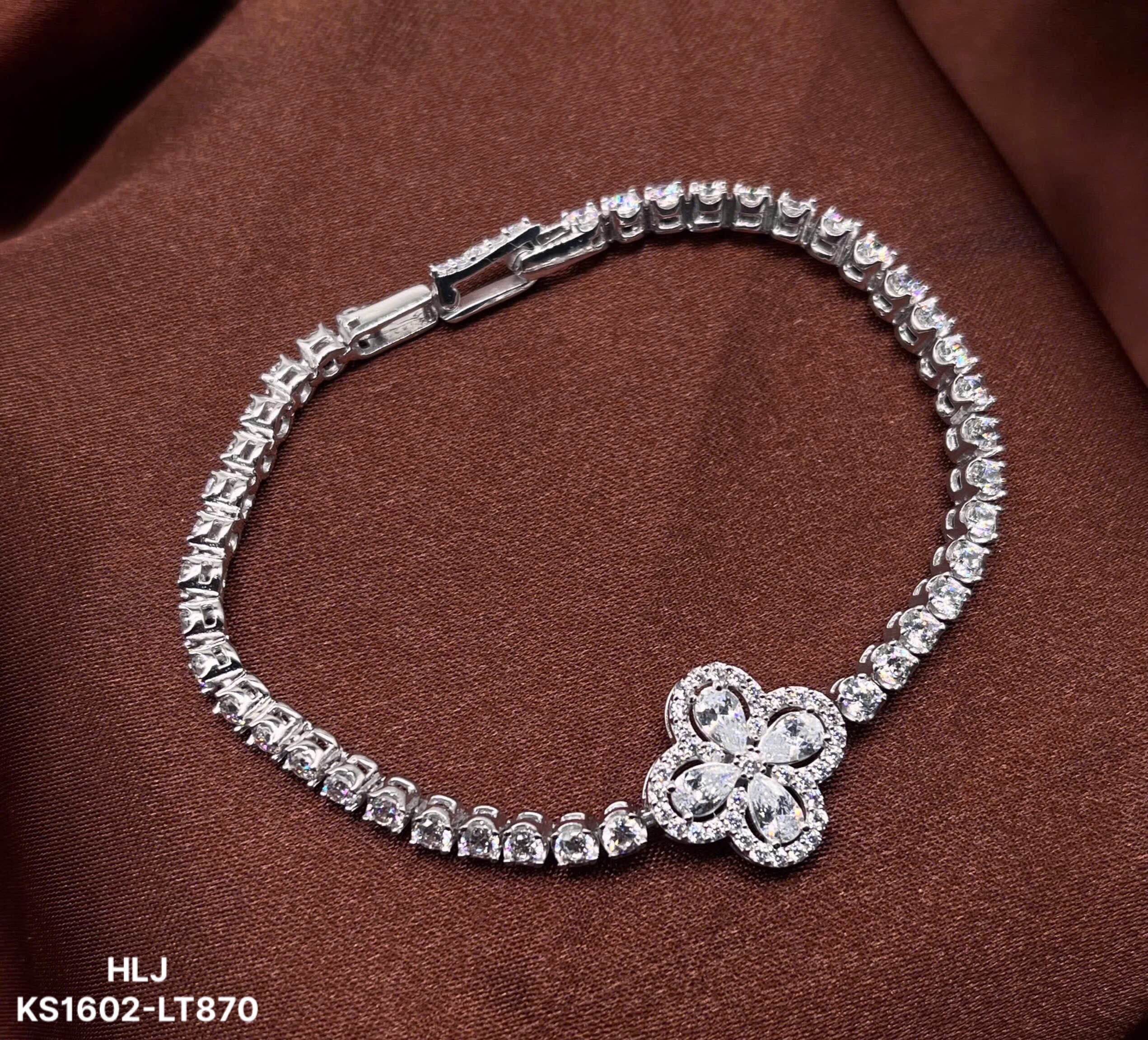 Silver bracelet with a floral clasp on a brown fabric background