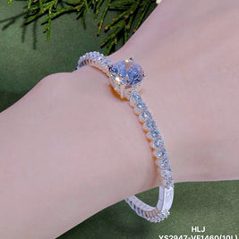 Silver bracelet with a large blue gemstone on a wrist against a green background